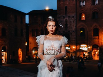 A bride in a white dress in the old town of San Gimignano.A girl walks around the city in Italy