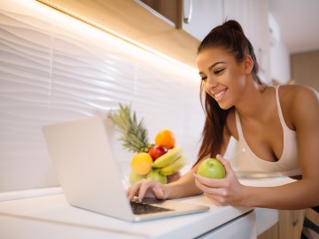 Fit smiling young woman with apple in modern kitchen